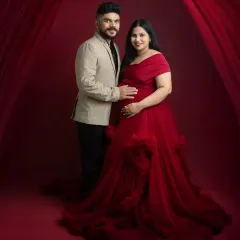 A classic, formal portrait of the expecting couple. The combination of his smart blazer and her dramatic red gown creates a sophisticated and timeless look.