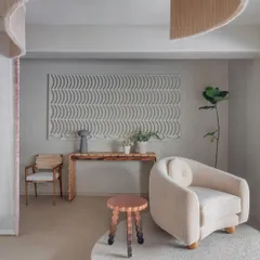 This vignette highlights the interplay of textures, from the soft, upholstered armchair to the rough-hewn wooden console and the intricate wall art. Each piece is placed on its own organic-shaped platform, elevating it from mere product to a piece of sculpture.