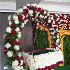 This cradle is part of the Krishna-themed decoration, fully covered in white chrysanthemums and red roses. It is suspended from a matching floral arch, creating a beautiful and safe space for the baby.