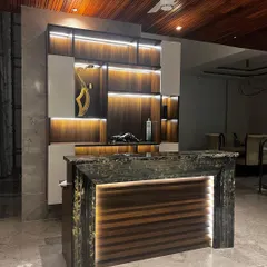 This custom-designed bar area features a unique bar counter with a textured, illuminated stone front. The back unit combines wood shelving with integrated LED lighting to highlight the display.
