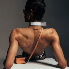 A full back view for a Calvin Klein accessories campaign. The pose and lighting are designed to draw attention to the bag and the defined musculature of the model.