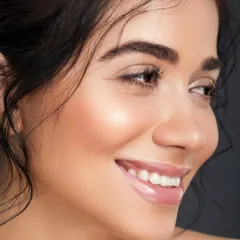 A profile shot capturing a natural, joyful smile. The light beautifully catches the highlight on the cheekbones, showcasing a healthy, "lit-from-within" glow.