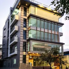 The same commercial building viewed at dusk, where the interior lighting highlights the structure's glass-heavy design and cantilevered sections.