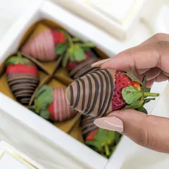 A close-up of a hand-picked, perfectly drizzled chocolate-coated strawberry, showcasing the quality and freshness.