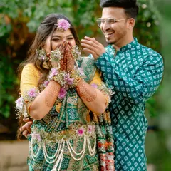 A joyful, candid moment from a traditional baby shower. The couple's laughter is infectious, and the bride-to-be looks radiant in her green saree and floral jewellery.