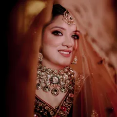 A classic bridal portrait, peeking through the veil. This soft, intimate shot highlights the bride's beautiful smile and the stunning kundan jewelry she's wearing.