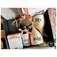 A sophisticated couple's hamper featuring 'Mr & Mrs' wine glasses, personalized luggage tags, and luxury bath products from The Body Shop and Zara.