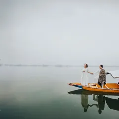 A wide shot of the couple on a traditional Shikara, seemingly floating on the calm, reflective waters. This image captures the peace and tranquility of a destination shoot in Kashmir.
