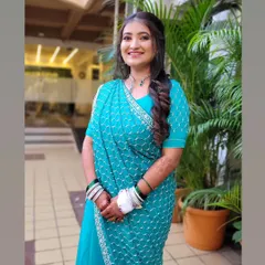 A smiling bride-to-be at her engagement, looking lovely in a turquoise saree styled in a modern mermaid drape.