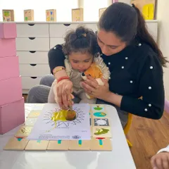 A teacher gently guides a child through a coloring activity. This one-on-one attention helps children feel secure and confident as they settle into the school environment.