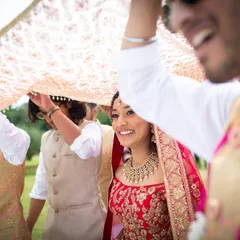A joyful bride makes her entrance under a traditional phoolon ki chadar held by her brothers. This is a classic candid wedding photography moment we love to capture.