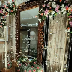 An ornate, vintage-style mirror serves as a welcome sign, adorned with hanging crystal beads and lush floral arrangements for a touch of old-world charm.