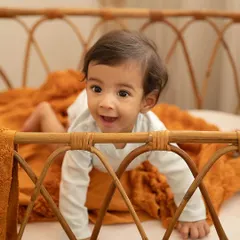 Peeking over the side of this beautiful cane bassinet, this little one's happy expression is priceless. My studio has a variety of props to create different looks for your session.