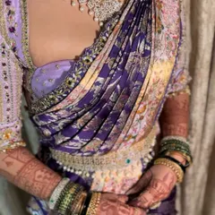 A close-up of a modern saree drape, showcasing the intricate pleating and how it complements the heavy jewellery and embroidered blouse.