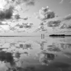 A minimalist black and white beach scene. The reflection creates a beautiful symmetry, making the sky and sand merge into one.