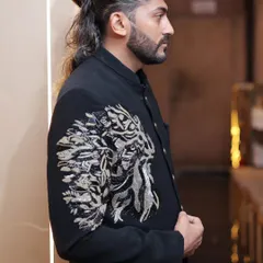 A side profile showcasing the detailed lion embroidery on the sleeve and shoulder of our black Jodhpuri suit. It’s a true statement piece.