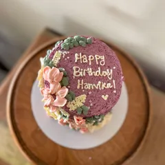 This tall barrel cake is a great example of my floral buttercream work. The textured purple frosting is adorned with hand-piped flowers in pastel pinks and yellows, creating a beautiful garden effect.
