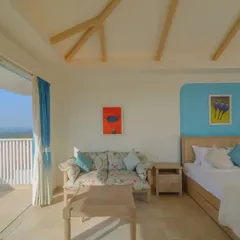 The master bedroom in Yuvraj Singh's Goa residence, featuring a minimal aesthetic with a neutral palette accented by shades of blue. The space opens onto a private balcony, reinforcing the home's connection to the serene natural landscape.