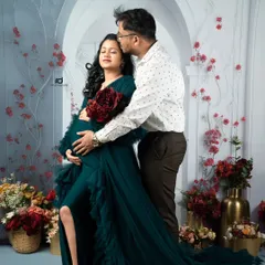 A tender kiss for the mom-to-be. Set against a floral backdrop, this shot in a beautiful green gown highlights the romance and anticipation of waiting for your baby.