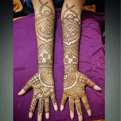 A perfectly symmetrical, full-coverage bridal mehandi that extends up to the elbows. This design features the groom's name, 'Tejas', hidden on the palm, surrounded by traditional Indian henna patterns.