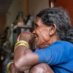 A candid, side-profile shot of the 'aaji'. This black and white photo focuses on the beautiful textures of her wrinkled skin and her gentle smile, telling a story of a life fully lived.