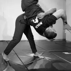 Takedowns are a fundamental part of controlling a physical confrontation. This black and white action shot captures the dynamic motion of a hip throw, a powerful technique taught in our grappling classes.