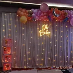 A closer look at the 'Oh Baby' backdrop. The combination of the warm neon sign and twinkling fairy lights creates a soft and celebratory ambiance.