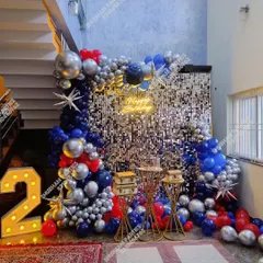 A bold and striking party decoration with a silver sequin wall and a balloon arrangement in red, blue, and silver chrome.