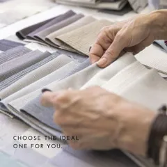 A client's hands exploring the texture and feel of different fabric books. The tactile experience is crucial in selecting the material for a custom-made garment.
