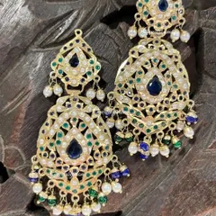 These Rajwadi-style earrings feature beautiful blue and green enamel work, known as meenakari, surrounded by pearls. They are designed to bring a touch of traditional Rajasthani grandeur to any bridal look.