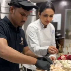 Teamwork makes the dream work. Here I am with a team member, meticulously placing sugar flowers on a large celebration cake.
