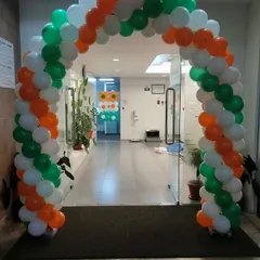 A balloon arch in the colors of the Indian flag (saffron, white, and green) for an Independence Day or Republic Day celebration at an office.
