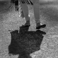 An artistic black and white shot focusing on the groom's shadow and his traditional footwear (juttis), telling a story of his journey to the wedding.