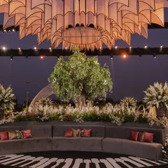 A curved grey velvet sofa faces a large tree centerpiece under a magnificent custom-built chandelier, part of the unique musical-themed reception.