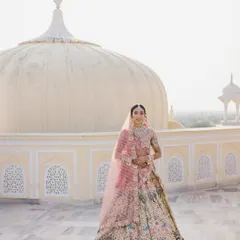 A stunning solo portrait of the bride on the palace rooftop. Her multi-colored lehenga stands out against the clean, classic architecture, creating a beautiful and elegant composition.