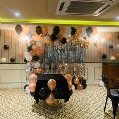 This wide shot shows the full 20th birthday party setup in the event space. I covered the cake table with a black cloth and placed balloons underneath to tie the whole look together.