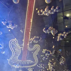 Rock on! This image shows a unique musical-themed ceiling decoration, featuring a large neon guitar and balloon "clouds." It's a perfect example of how we can transform an entire space, including the ceiling, to fit a creative theme.