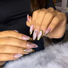 This design is pure luxury. It features a soft pink and white marbled base with brilliant gold chrome tips and delicate, hand-painted gold starbursts.