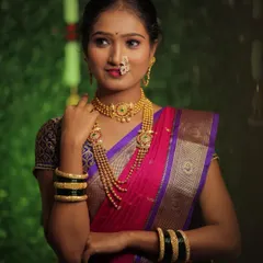 The pride of being a Marathi mulgi shines through in this look. Here, the bride is dressed in a beautiful pink and purple Nauvari saree with traditional gold jewelry, including a choker and layered necklaces.