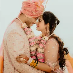 An intimate forehead-to-forehead pose, capturing the deep connection between the bride and groom. The soft pastel colors of their outfits and the floral garlands add to the romance.