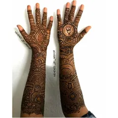 A full view of a personalized bridal mehendi, featuring the couple's initials inside interlocking rings on one palm and a custom motif on the other.