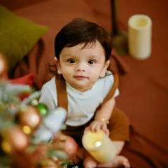 A close-up of this sweet baby enjoying our Christmas setup. The warm lighting and festive props create a magical holiday mood.