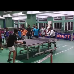 A player practices his serve on one of our new professional tables while others watch on. Our training sessions often include focused drills on specific techniques like serving and receiving, which are fundamental to the game.