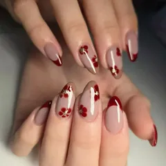 A beautiful and elegant hand-painted floral design. This set features delicate red flowers with gold foil centers on a nude base, paired with a classic red French tip.