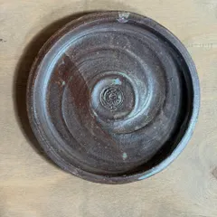 A handmade stoneware side plate with a unique spiral pattern, perfect for snacks or as a coaster. The glaze was developed over several months at the studio, and its color varies with each application.