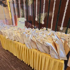 An organized and beautifully presented gift station for guests. The table is elegantly draped in yellow fabric, with a simple sign to guide attendees. It’s a small but important detail that ensures a smooth and welcoming experience.