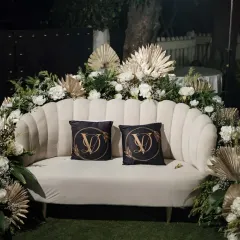 The happy couple deserves a special spot. We created this elegant seating area for the bride and groom at their Sangeet, featuring a classic white sofa, lush floral arrangements, and custom monogrammed pillows.