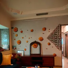 A wide view of a traditional kolam mural I painted in a client's living room. The design, reminiscent of patterns drawn on a grandmother's floor, brings a sense of heritage and celebration into a modern home. The scattered marigold flowers add a feeling of warmth and festivity to the space.