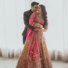 A warm and romantic embrace against a softly lit window, highlighting the couple's joy and the intricate details of their engagement attire.