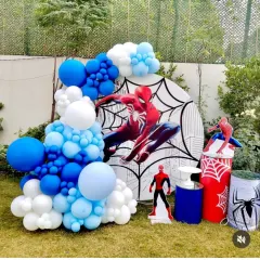 A dynamic outdoor Spider-Man theme, perfect for a garden party. This decoration includes a custom backdrop with a city skyline, an organic balloon arch in signature red, blue, and white, and multiple Spider-Man character cutouts.